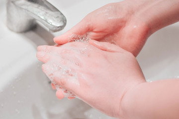 Female hands and fingers close up washed with soap and foam and water. Hygiene and coronavirus prevention concept. 