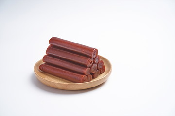 Delicious hawthorn sticks in a wooden tray against a white background