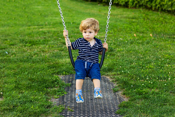 Little boy on a swing. Cute child outdoors. 