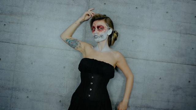 Nice girl with body art tattoo patterned skull chicano style on her face looking at the camera. Halloween party and mexicans death day santa muerte concept