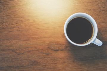 Closed up image of hands holding a cup of coffee with background of wood table.