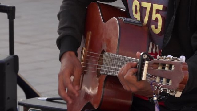 Close up of black skin male Arabian hand playing a guitar during a live performance outside. Street performer 