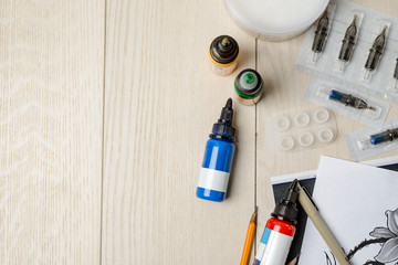Tattoo artist's supplies on wooden table with copy space