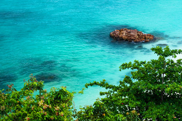 Large stones in the emerald sea The wave lapped the coast with trees along the coast In the Andaman Sea At Sunset Beach, Koh Lipe, Satun, Southern Thailand