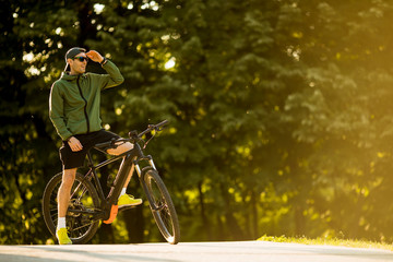 Young man with ebike, mountain bike with electric battery in the park