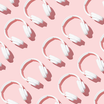 Pattern white headphones on modern pale pink table top view isometry flat lay. Free space for creative design text and content.