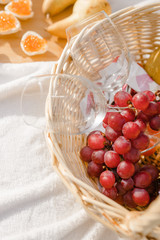 Basket with red grapes and glasses on a blanket