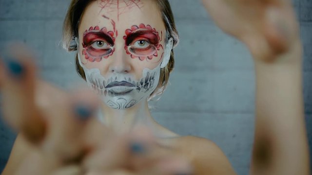 Nice girl with body art tattoo patterned skull chicano style on her face looking at the camera. Halloween party and mexicans death day santa muerte concept