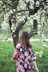 Fototapeta na wymiar a young girl in a pink dress walks in the spring garden