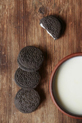 on a brown background a cup of milk and chocolate chip cookies
