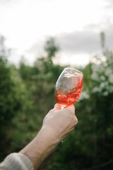 A glass of red wine in hand against the background of the sunset