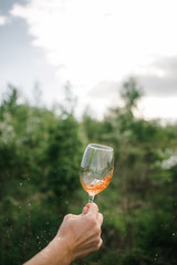 A glass of red wine in hand against the background of the sunset