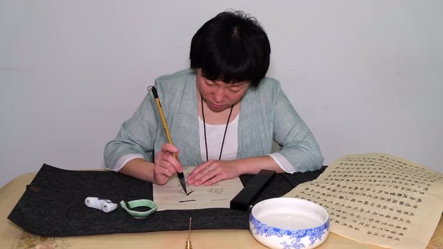 Young woman practicing Chinese traditional calligraphy at home