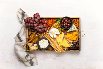 Cheese board with grapes, nuts and dried fruits, overhead view