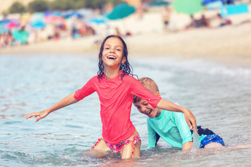 Happy kids playing in sea during summer vacation