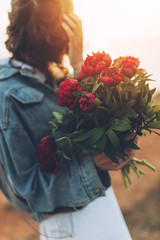 Beautiful girl in a hat on nature with a bouquet of peonies.