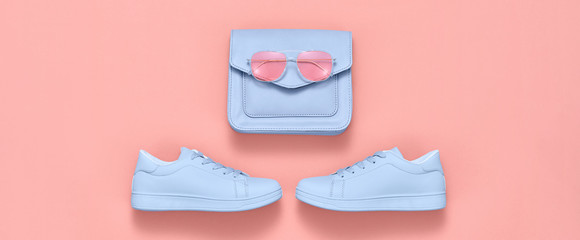 Fashion accessories minimal flat lay. Trendy shoes sneakers, handbag, sunglasses. Pop art concept. Woman fashionable accessories on coral, top view, banner. Creative design color