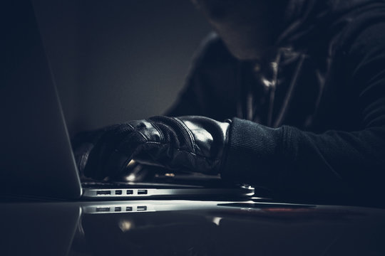 Masked Computer Hacker In Dark Room.