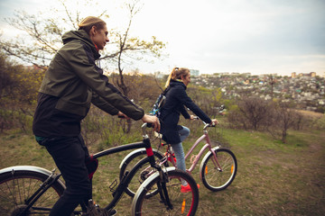 Obraz premium Best friends having fun near countryside park, riding bikes, spending time healthy. Calm nature, spring day, positive emotions. Sportive, active leisure activity. Traveling or walking together.