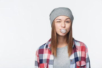 Smiling teen girl blowing bubblegum winking at you