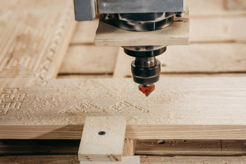 Close-up of cutting wood on a CNC milling machine in garage
