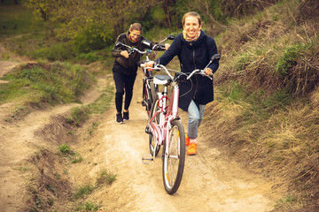Best friends having fun near countryside park, riding bikes, spending time healthy. Calm nature, spring day, positive emotions. Sportive, active leisure activity. Traveling or walking together.