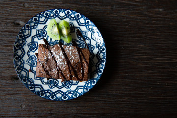 Chocolate Brownie Dessert Cake with Kiwi on a Blue Plate Wooden Tow