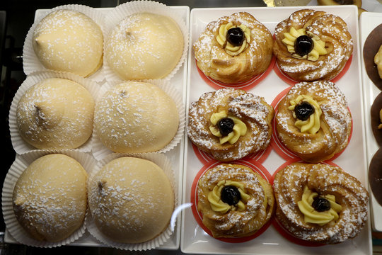 Zeppole and tette delle monache for breakfast in a shop window of an Italian bar