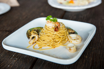 Seafood spaghetti in a white plate on an old wooden table