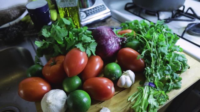 close up view of various healthy nutritious vegetables siting on a kitchen table. tomatoes onions garlic and lime make the recipe for delicious pico de gallo