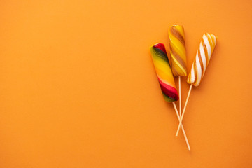 Colored sweet lollypops on orange