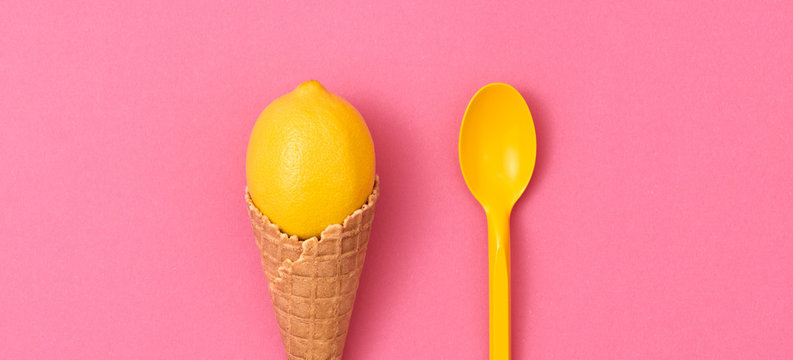 Lemon fresh fruit in ice cream cone. Fashion summer minimal design, pastel color. Pop art. Citrus lemon flat lay on pink. Creative art fashionable concept, summertime, lemon banner