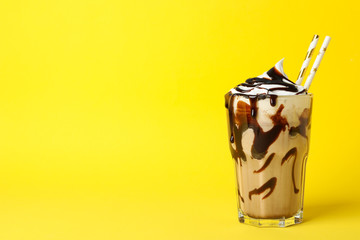 Glass of chocolate milkshake on yellow background. Summer drink