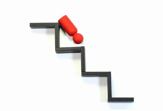Wooden figurine falling from the steps. Concept of leadership failure.