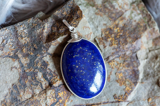 Beautiful lapis lazuli mineral stone pendant on rocky background