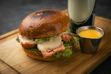 hamburgers with salmon and beer on wooden board and dark background
