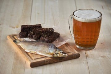 A mug of beer and an assortment of snacks on a wooden table.