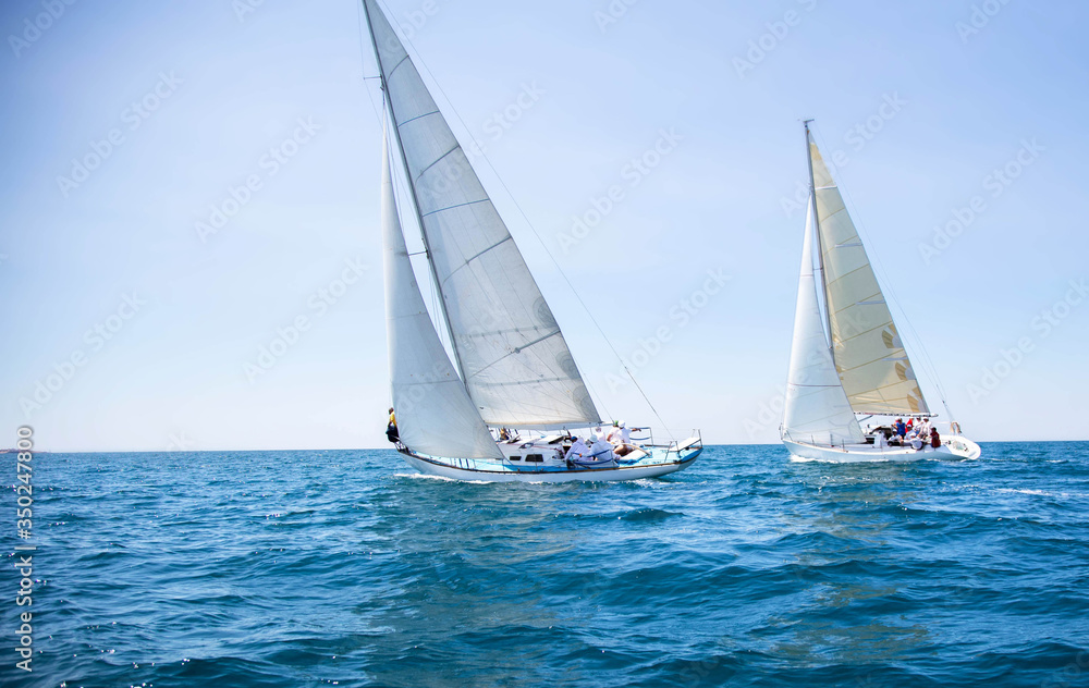 Poster two white motor yachts with raised sails take part in the regatta. a strong wind tipped the ship. wa