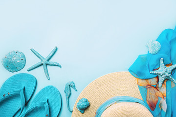 Summer fashion on blue and coral background. Blue flip flops, seashells, and straw hat. Flat lay, top view with copy space.