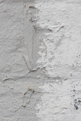 The old rough street wall is painted in white and gray with dark splashes. There is a place for text. A vertical photo was taken close-up for your design.