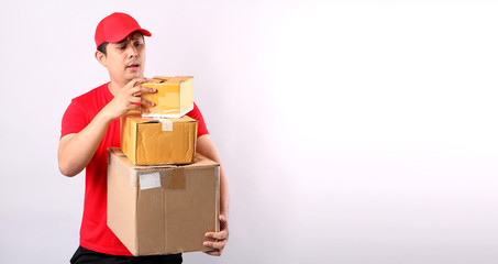 Image of a happy young delivery Asian man in red cap standing with parcel post box isolated over white background in studio With copy space.