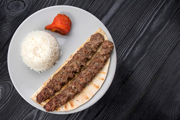 meat on pita bread with rise on a black wooden background