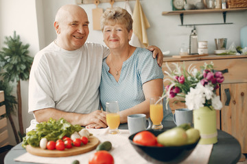 Coyple in a kitchen. Grandparents sitting at home. Woman with vegetables