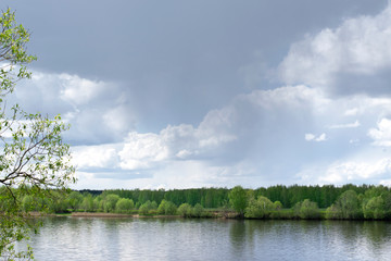 Stormy sky reflected in the river and forest in the background. Before the rain