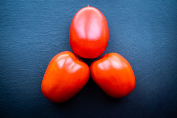 Top view of three fresh tomatoes on a dark background. Healthy and natural food concept,