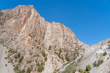 The beautiful mountain trekking road with clear blue sky and rocky hills in Fann mountains in Tajikistan