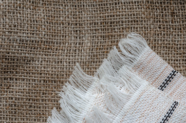 Cloth napkin with fringe on burlap.