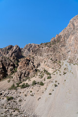 The beautiful mountain trekking road with clear blue sky and rocky hills in Fann mountains in Tajikistan