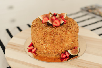 Honey cake. Fig cake. Strawberries on the cake. Cake on a wooden tray. 
