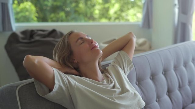 Girl closed hands behind hand breathing fresh air resting in comfortable sofa at home Calm young woman dozing daytime nap on couch with closed eyes
